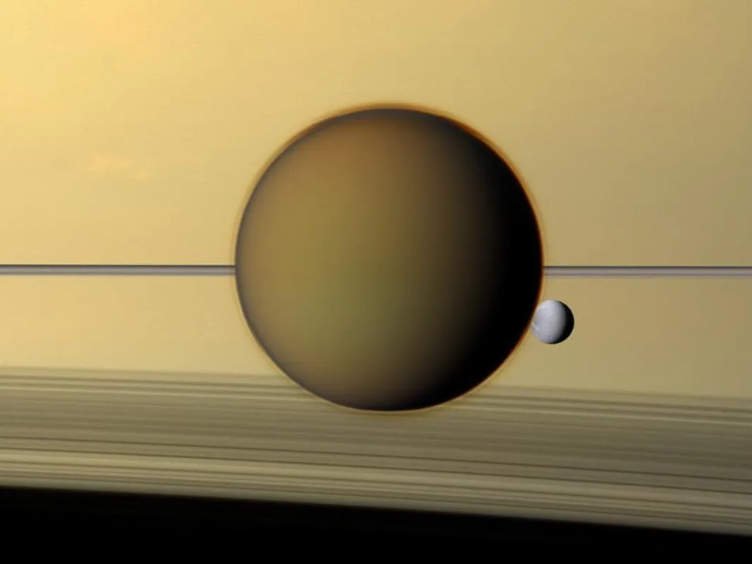 Titan nähtynä Saturnuksen pintaa vasten, mukana myös pienempi kuu Dione